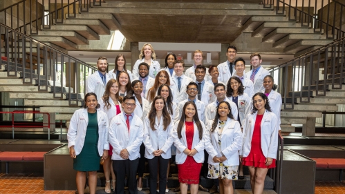 Incoming RWJMS students stand on a staircase at the school's white coat ceremony