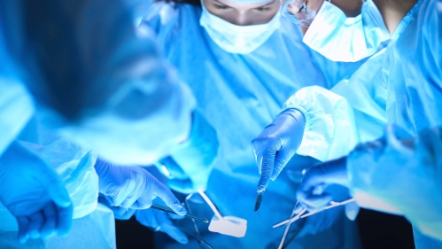 Doctors holding instruments look down at a patient in an operating room
