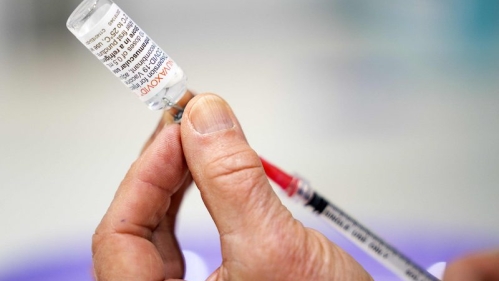 A health care provider draws a vaccine from a vial into a syringe