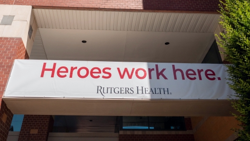 Exterior of a Rutgers Health building with a sign that says Heroes Work Here.