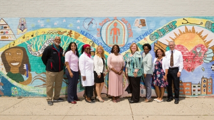 Eric Chandler health center staff stand in front of a mural in New Jersey