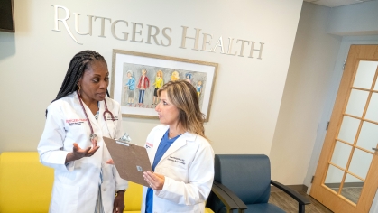 Two doctors in white coats talk in a Rutgers Health office