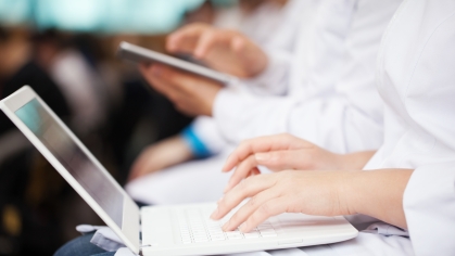 Medical school students type on laptops and tablets.
