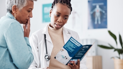 A doctor and patient look over a pamphlet in an exam room
