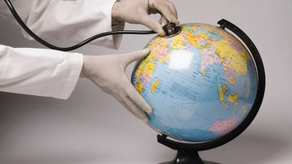 doctor puts stethoscope to globe