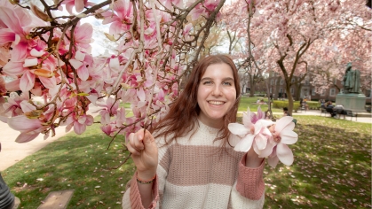 Talia Rosen standing in the pink blossoms of a tree