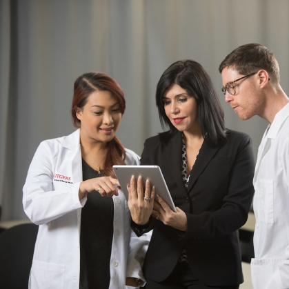 School of Health Professions students and a professor look at a tablet screen