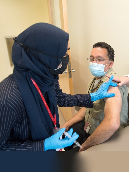 A Vax Corps member administers a covid vaccine to a Rutgers environmental services employee