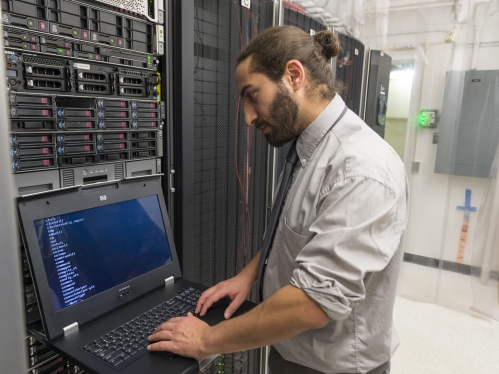A person types on a computer in a bioinformatics server room 