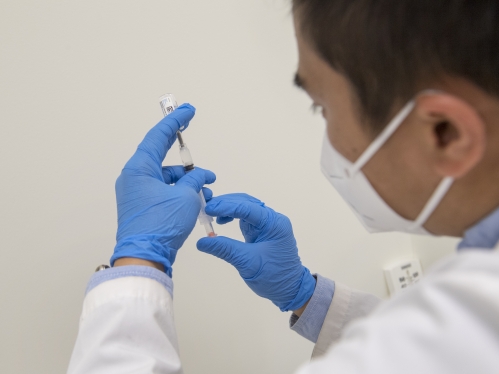 A pharmacist draws a covid vaccine into a syringe
