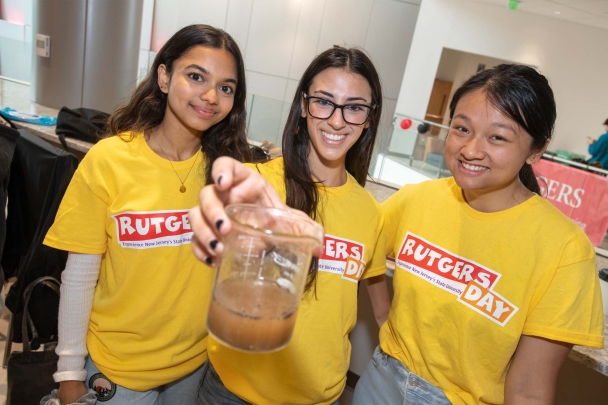 Students wearing yellow Rutgers Day t-shirts holding a glass of water 